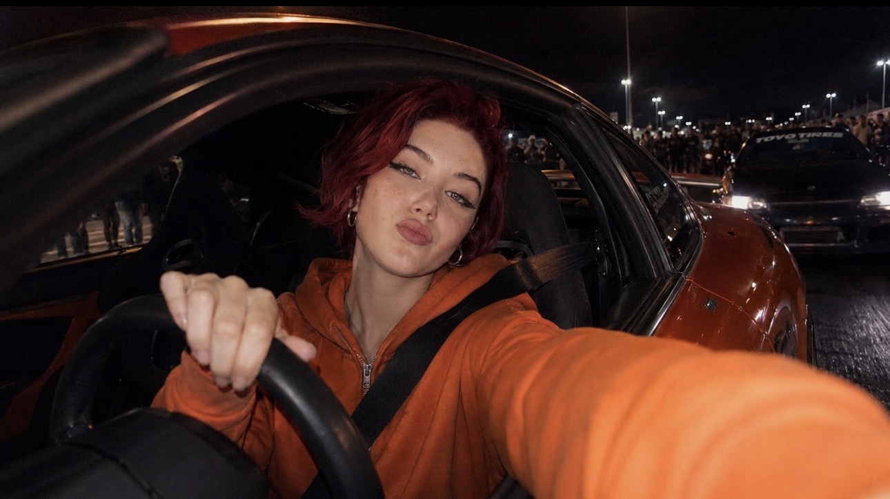 Alice Kwong filming inside an orange car at night